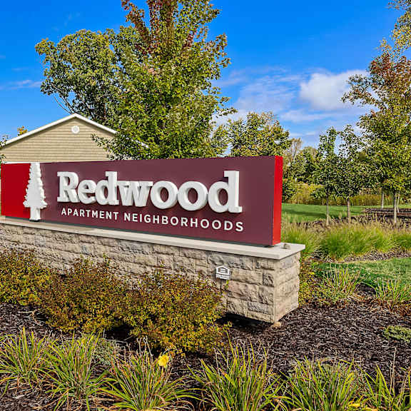 a sign for redwood apartment neighborhoods is displayed in front of a building.