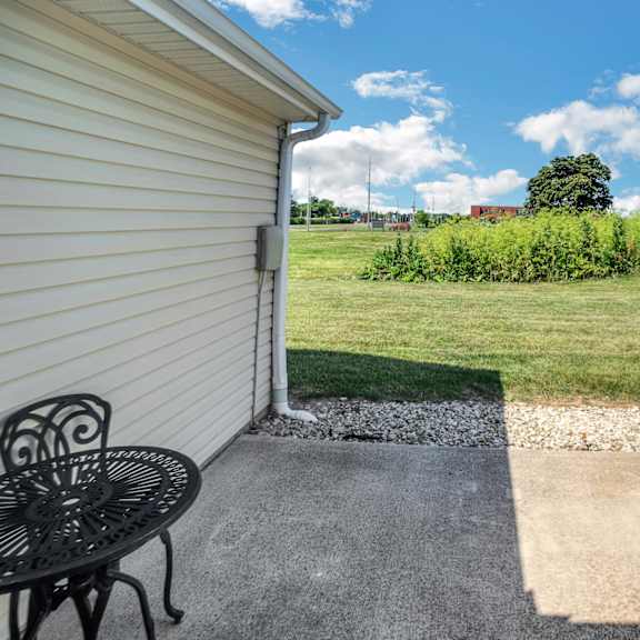 a patio with a table and chairs is in front of a house.