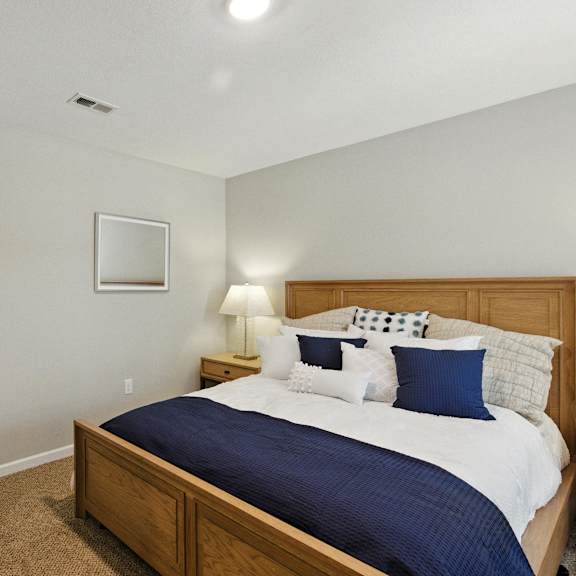 a bedroom with a bed, nightstand, lamp, and door.