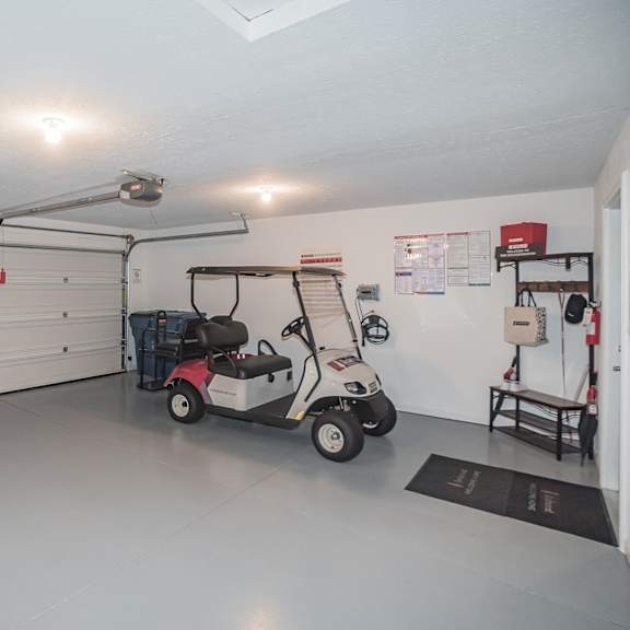 a golf cart is parked in a garage with a white wall and a black mat on the floor.