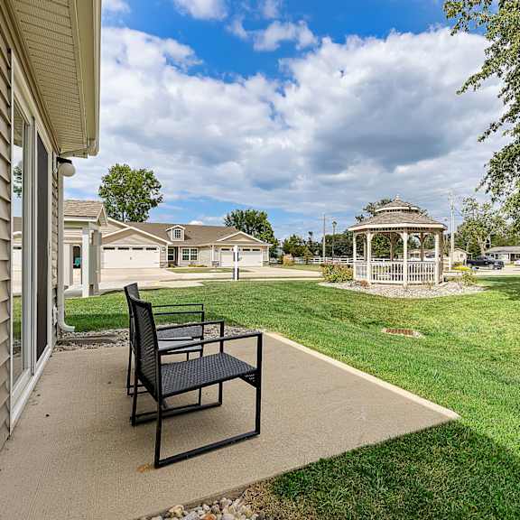 a black chair is on a concrete patio outside a house.