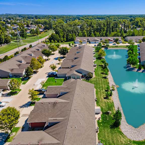 a bird's eye view of a residential area with houses and a pond.