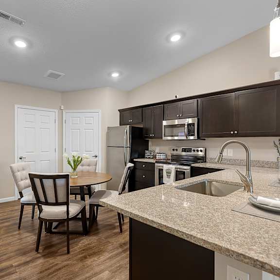 a kitchen with brown cabinets and a table with chairs.