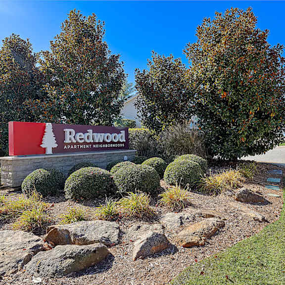 a sign for redwood apartment neighborhoods is displayed in front of some trees.