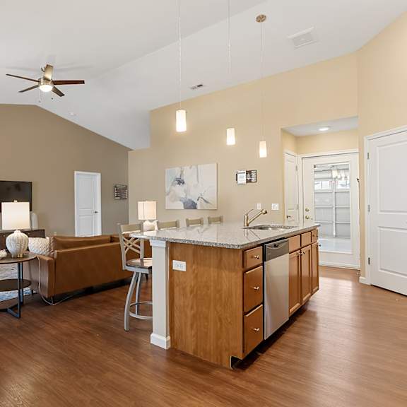 a modern kitchen with wooden floors and a ceiling fan.