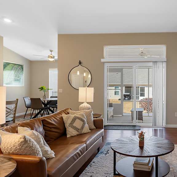 a living room with a brown leather couch and a round table in the center.