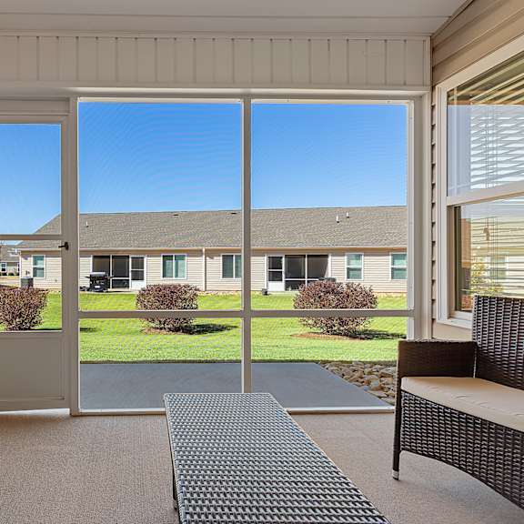 a patio with a couch, chair, and sliding glass doors.