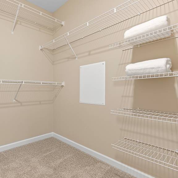 a room with a carpeted floor and a wall-mounted shelf with towels.