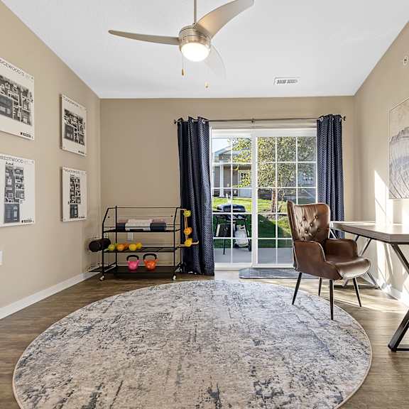 a room with a rug, a chair, a table and pictures on the wall.