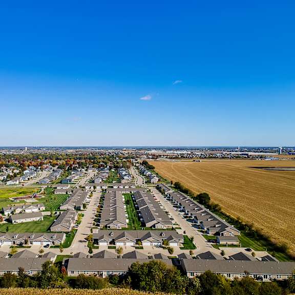 a suburban neighborhood with rows of houses and a field in the foreground.