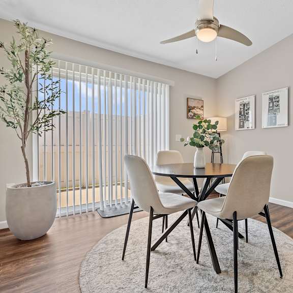 a dining room with a table, chairs, and a plant.