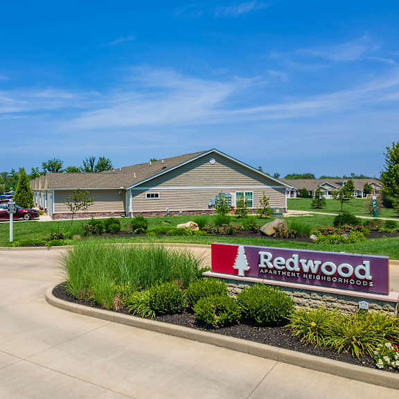 the image shows a sign for redwood apartment neighborhoods in front of a building.