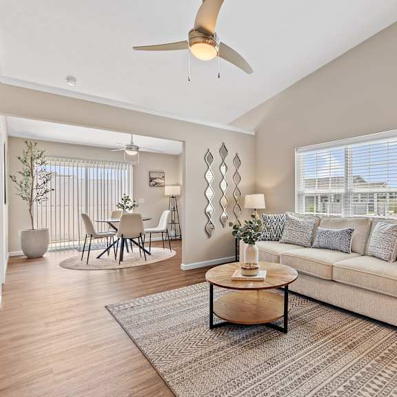 a living room with a white couch, a wooden coffee table, and a ceiling fan.