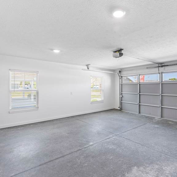 a spacious garage with a concrete floor and a grey garage door.