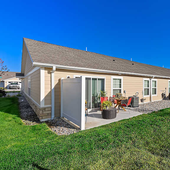 a house with a grey roof and a white wall with a red chair outside.