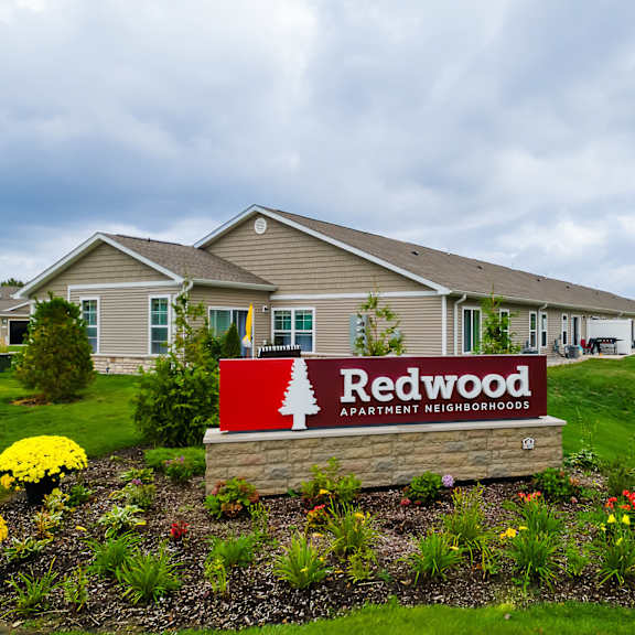 a redwood apartments sign is in front of a building.