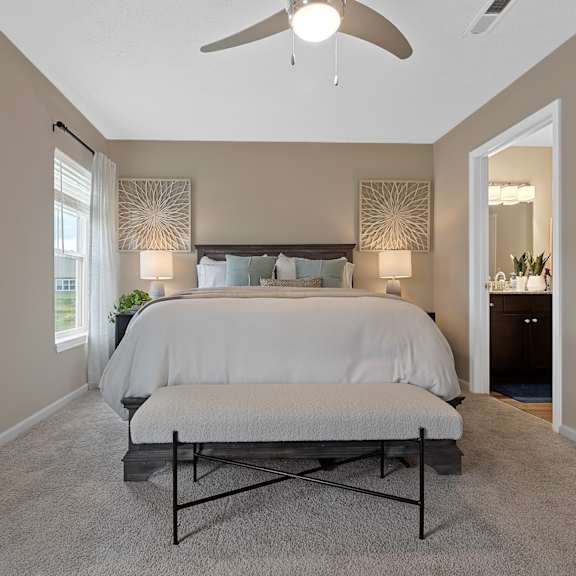 a bedroom with a bed, a bench, and a ceiling fan.