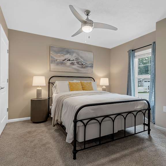 a bedroom with a bed, two lamps, and a painting on the wall.