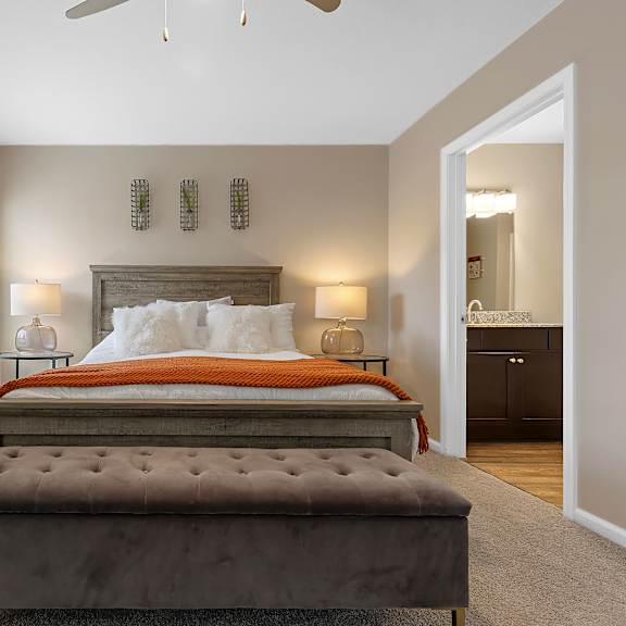 a bedroom with a large bed and a bench in front of it.