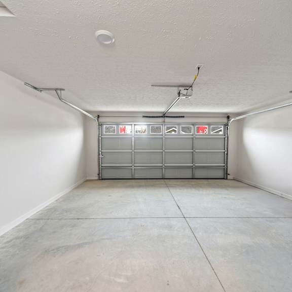 a white room with a concrete floor and a metal gate in the middle.