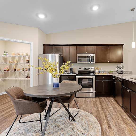 a kitchen with brown cabinets and a round table with chairs.