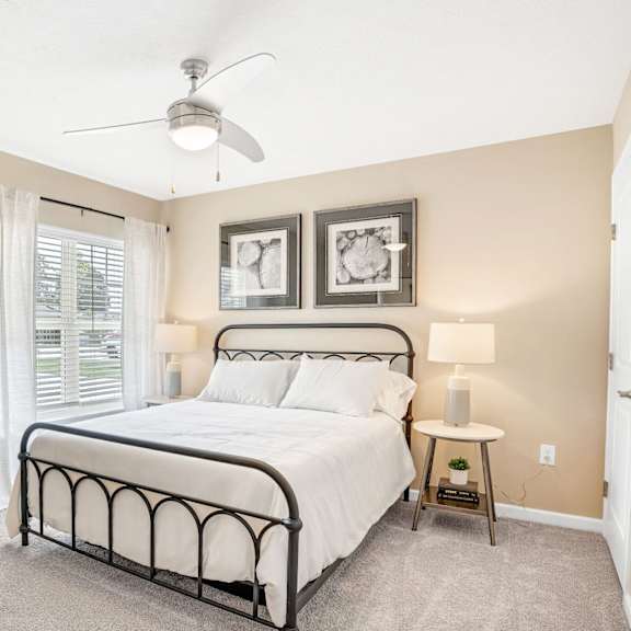 a bedroom with a bed, nightstand, and a ceiling fan.