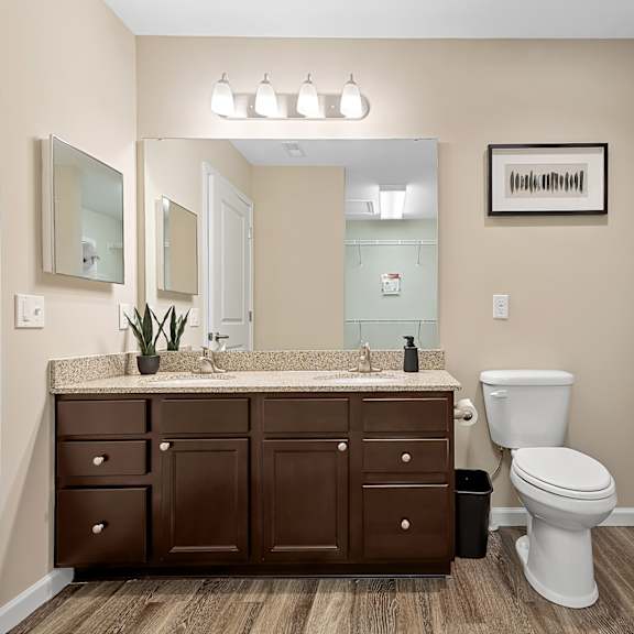 a bathroom with a brown vanity and a white toilet.