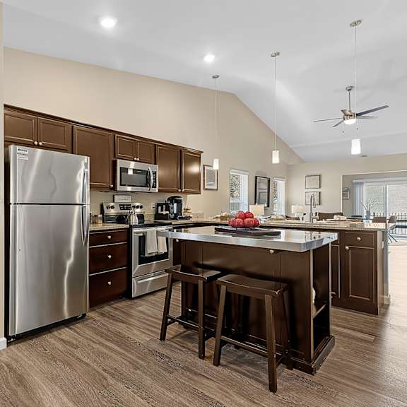 a kitchen with a refrigerator, stove, and bar stools.