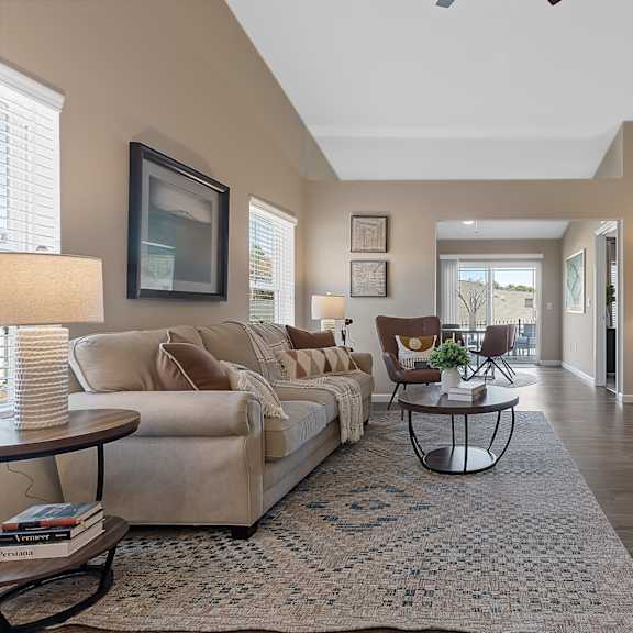 a living room with a beige couch, a coffee table, and a flat screen tv mounted on the wall.