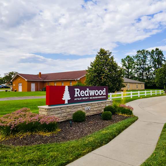the image shows a sign for redwood apartment homes in front of a building.