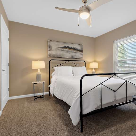 a bedroom with a bed, two lamps, and a painting on the wall.