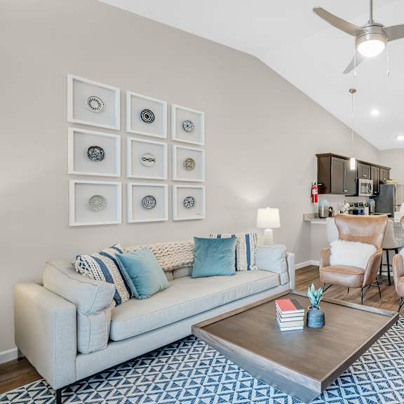 a living room with a white couch, a coffee table, and a ceiling fan.