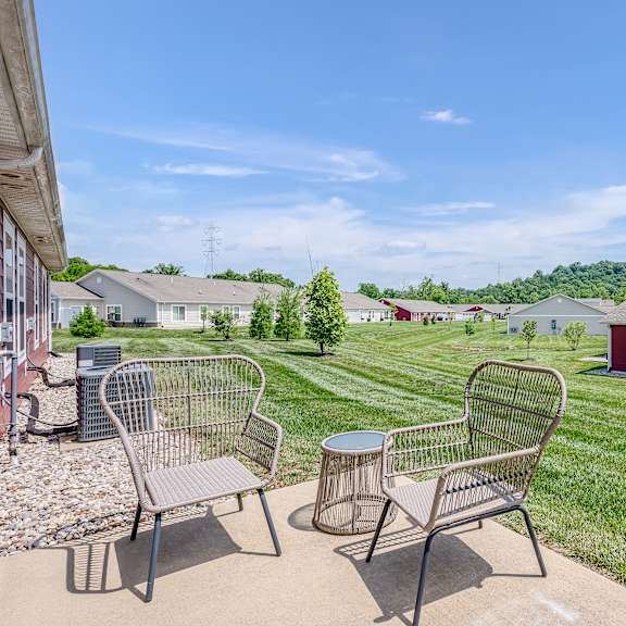 a patio with two chairs and a table is in front of a house.