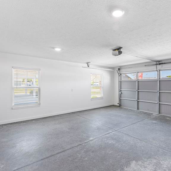 a large empty room with a grey floor and a grey garage door.