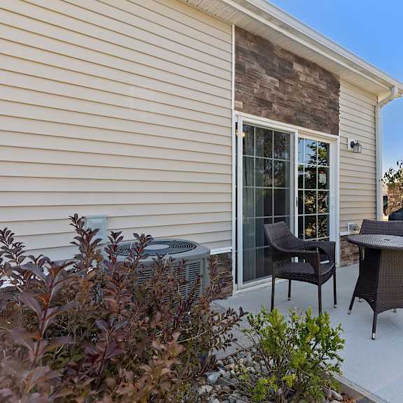 a patio with a table, chairs, and a grill.