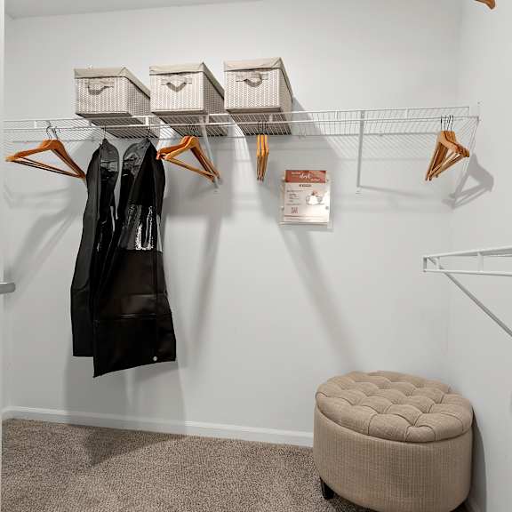 a white closet with a black coat hanging on a hanger.