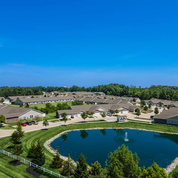 a large pond in the middle of a grassy area surrounded by houses.