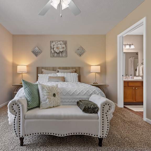 a bedroom with a bed, two lamps, and a ceiling fan.