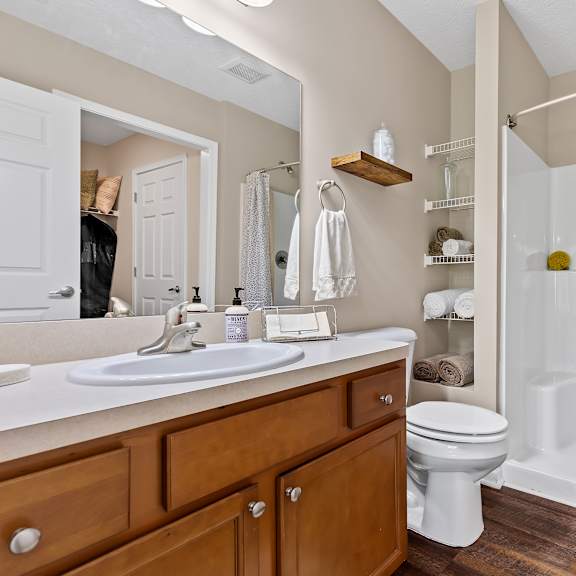 a bathroom with a white sink, toilet, and shower.