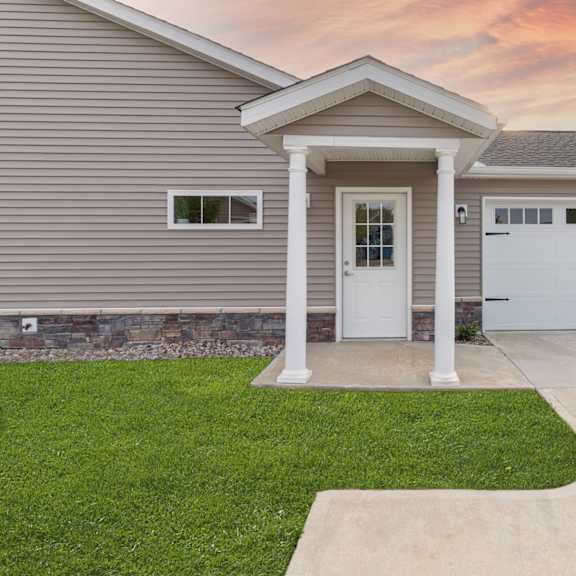 a house with a grey siding and a white door and garage door.