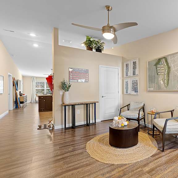 a living room with a brown rug and a ceiling fan.