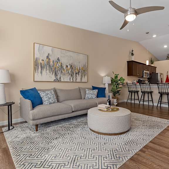 a living room with a grey couch, a round coffee table, and a painting on the wall.