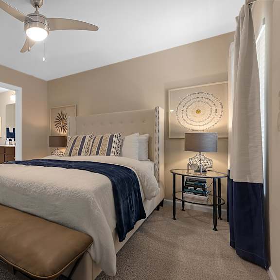 a bedroom with a bed, a bench, and a ceiling fan.