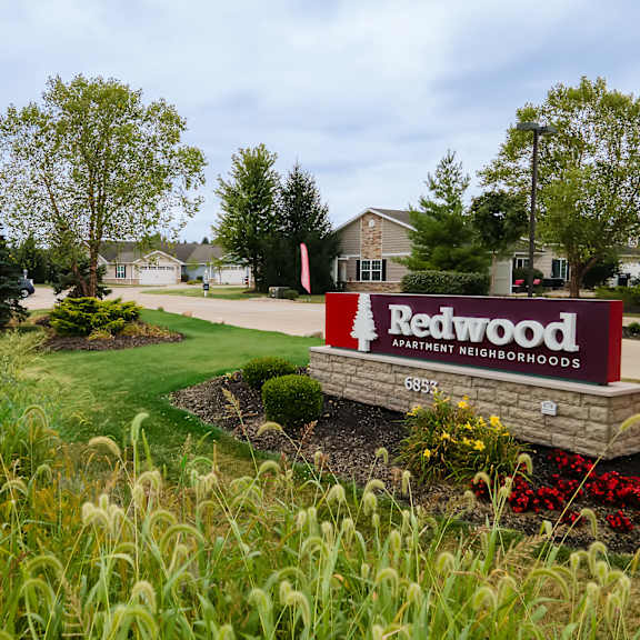 a sign for ratwood apartment neighborhoods is in the foreground of a well-kept lawn.