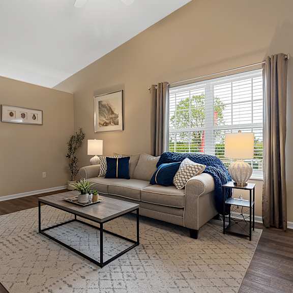 a living room with a couch, coffee table, and a window with blinds.