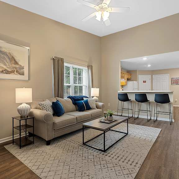 a living room with a beige couch, a coffee table, and a painting on the wall.