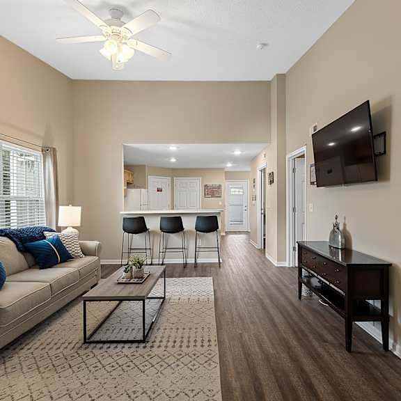 a living room with a beige couch, a coffee table, and a flat screen tv mounted on the wall.
