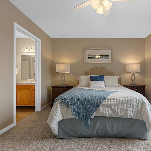 a bedroom with a bed, two lamps, and a ceiling fan.
