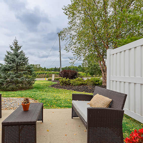 a patio with a white fence and a table with two chairs.