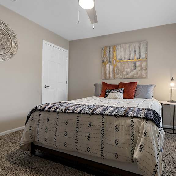 a bedroom with a bed, a painting, and a ceiling fan.